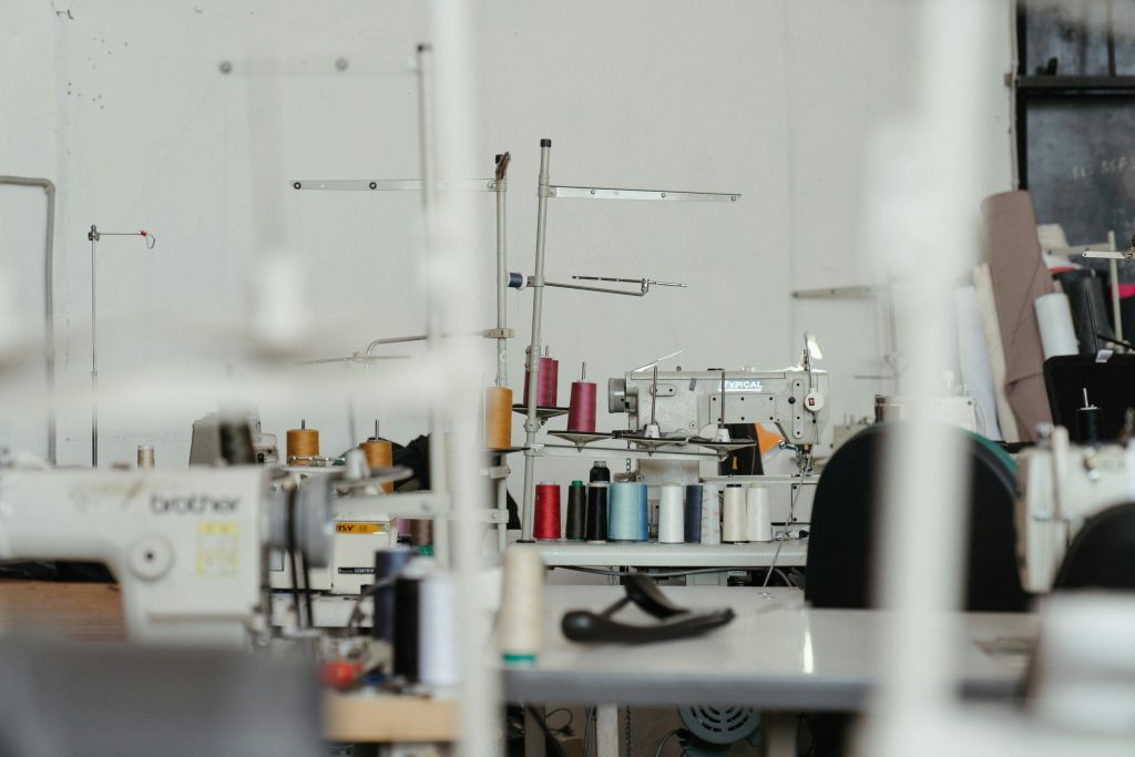 Local versus offshore manufacturing A busy sewing workshop with various sewing machines and thread spools, showcasing textile production.
