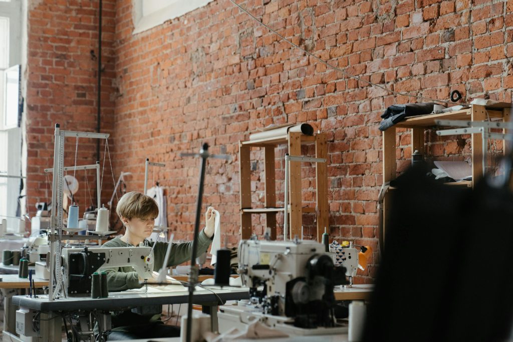 Minimum Order Quantities explained A sewing workshop with a focus on modern machines against a rustic brick wall, showcasing craftsmanship.